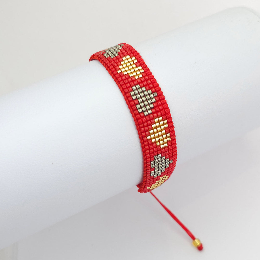 Pulsera tejida roja con chaquira de corazon dorados y plateados